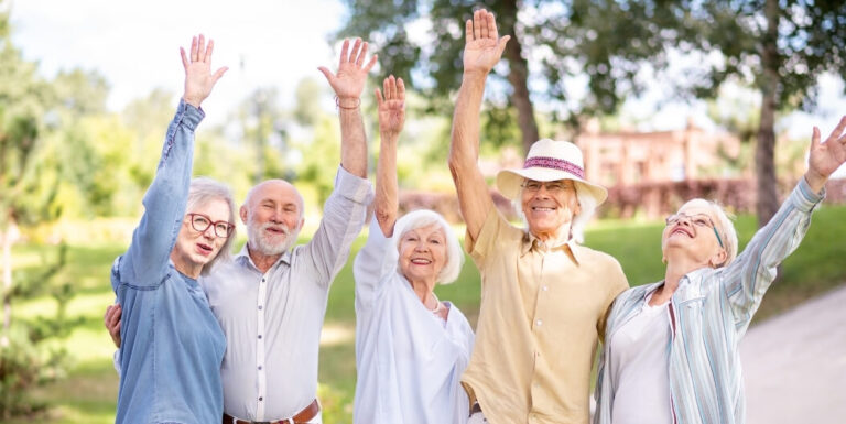 Group of Seniors Raising Their Arms Together in a Park at an Independent Living Facility