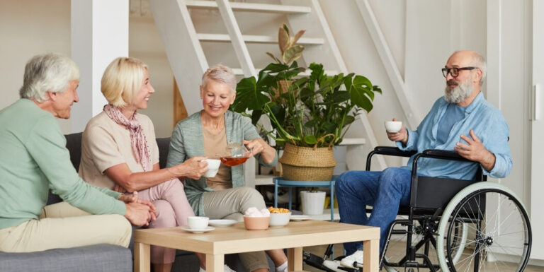 Group of Seniors Having Tea with a Wheelchair User at an Assisted Living Facility